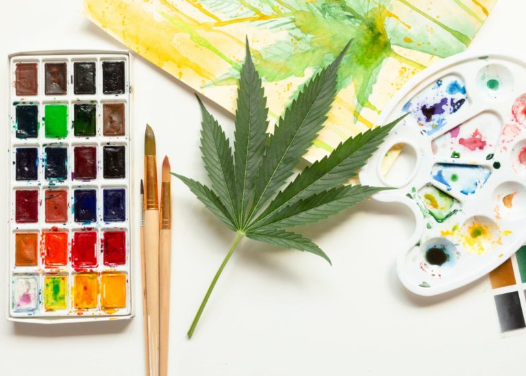 Painting art supplies next to a cannabis leaf