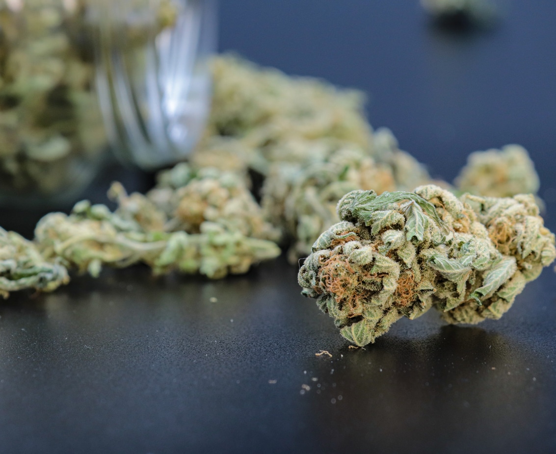 marijuana buds in glass jar on black background with copy space