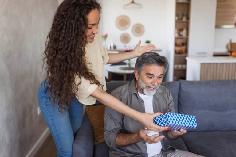 Young latin woman surprising her father with a present for father's day