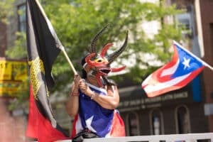 Chicago, Illinois, USA - June 16, 2018: The Puerto Rican People's Parade, woman wearing a traditional mask from puerto rico, wearing the puerto rican flag