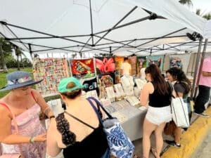 Miami, Florida, USA - January 13, 2023: Nationals and Internationals tourists walking and enjoying a street market at Ocean Drive; looking to buy some pieces of Arts in a cloudy winter day at South Beach.