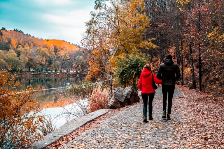 Couple walking by the lake in the forest during the autumn season